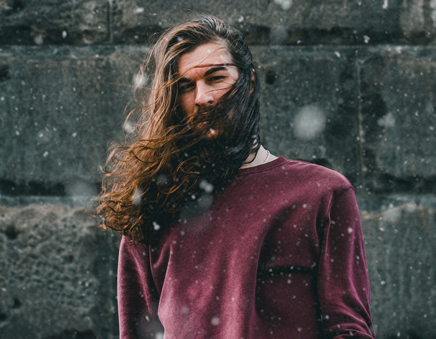 Man with dark eyes and long, dark hair blowing in the wind